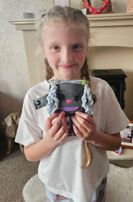 girl holding a softie that she has sewn for a friend